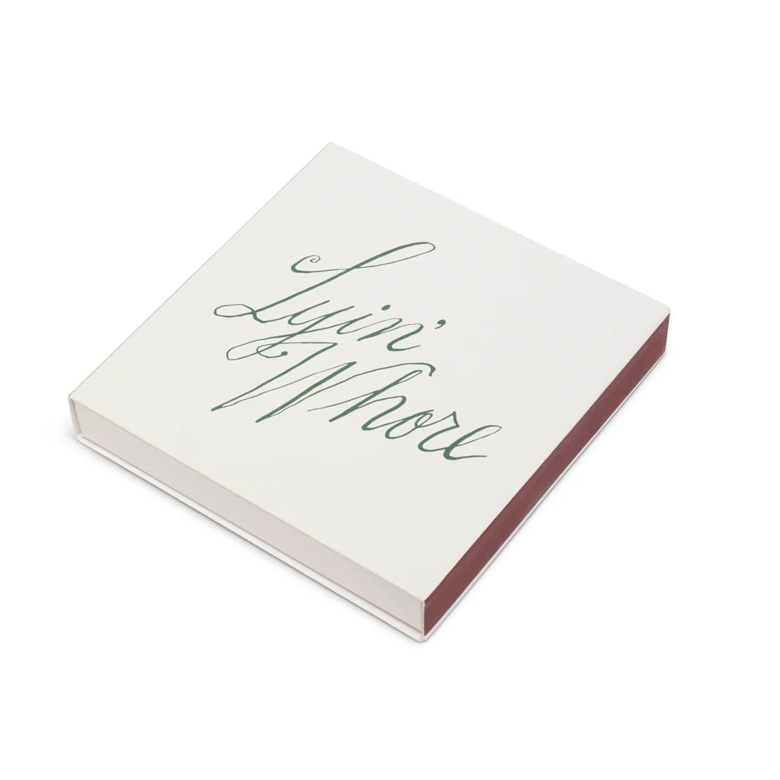 White square matchbox with Lyin' Whore green cursive script, angled to show the striker side