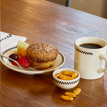 Muffin with fruit, coffee, and nuts on a wooden table