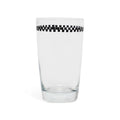 Clear juice glass with a black and white checkerboard band below the rim, side view