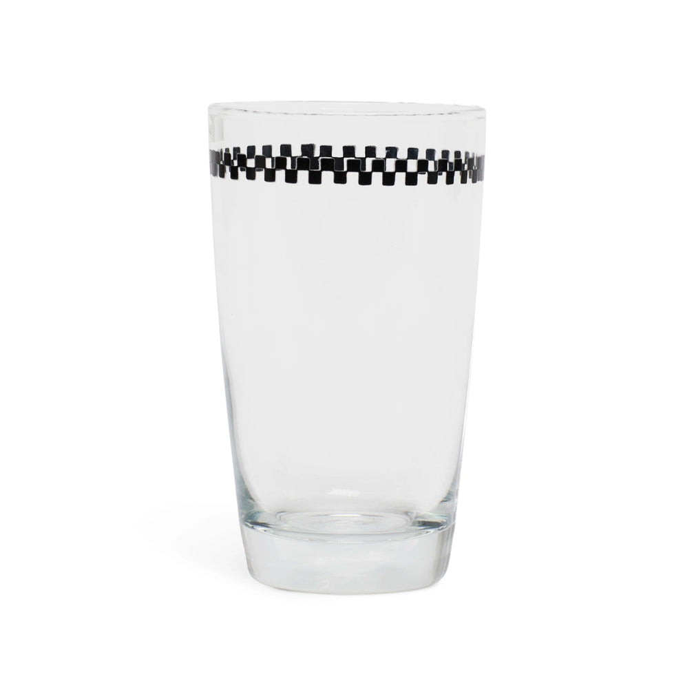 Clear juice glass with a black and white checkerboard band below the rim, side view