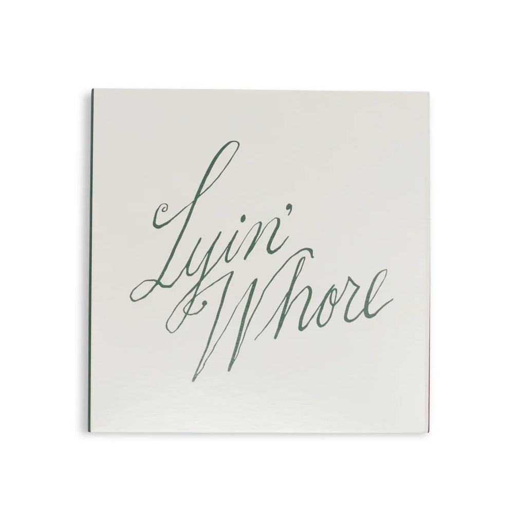 White square matchbox from above with Lyin' Whore in green cursive script