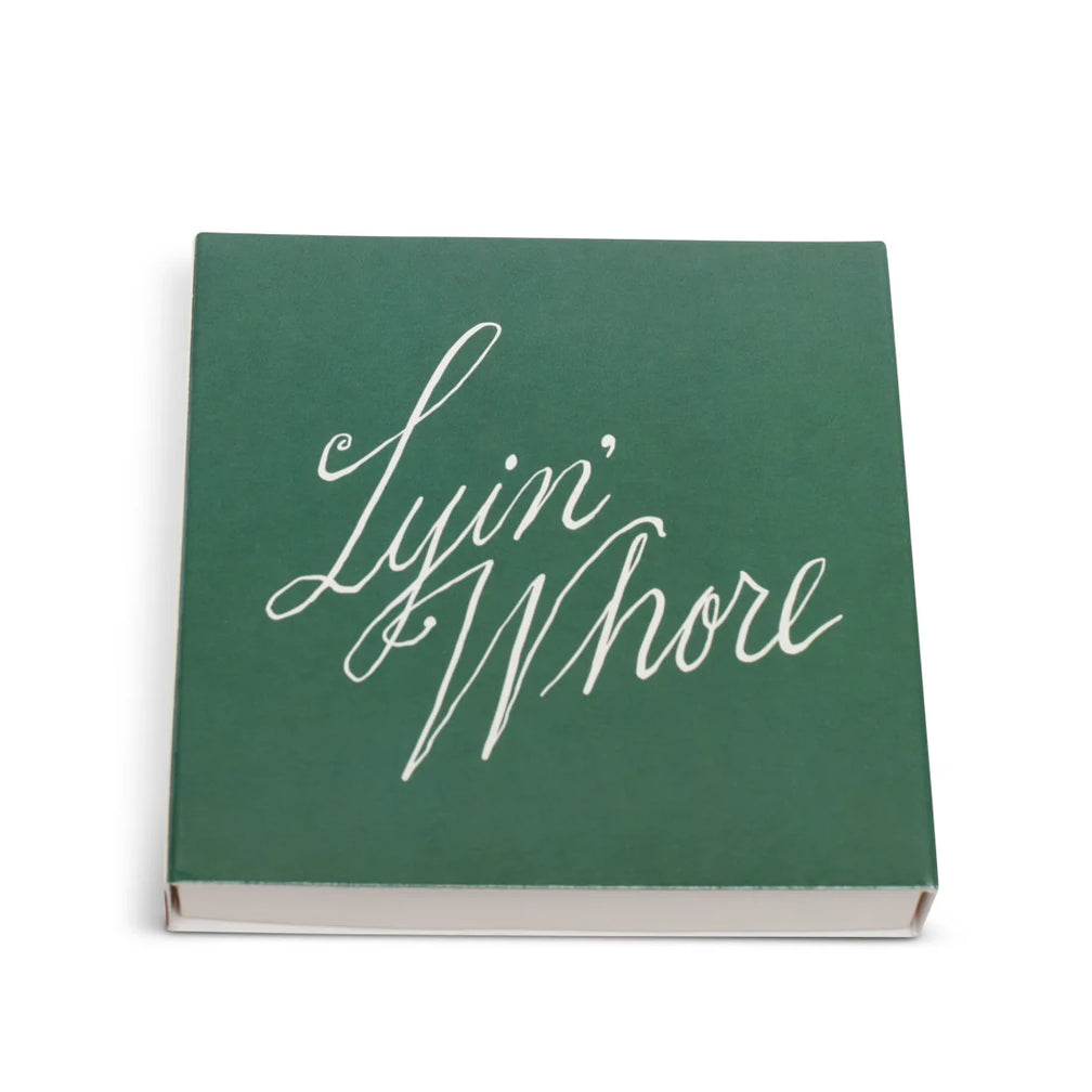 Green square matchbox from above with Lyin' Whore in white cursive script