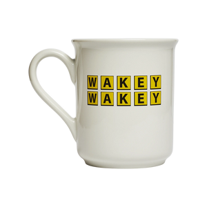 White ceramic coffee mug featuring the phrase “WAKEY WAKEY” in bold yellow block lettering. Funny morning mug designed for coffee lovers, early risers, and anyone needing an extra wake-up call. Front view.