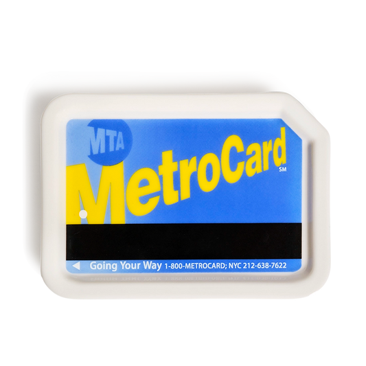 Blue ceramic MetroCard tray styled like an MTA MetroCard, with bright blue face, oversized yellow MetroCard lettering, black magnetic stripe, and raised white rim; compact catchall for keys, jewelry, coins, or desk essentials, shown from above.