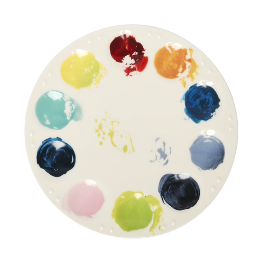 Round ceramic artist palette plate featuring colorful paint dabs arranged around the rim, inspired by a painter’s mixing palette. Decorative serving plate for snacks, appetizers, desserts, and creative entertaining. Top view.