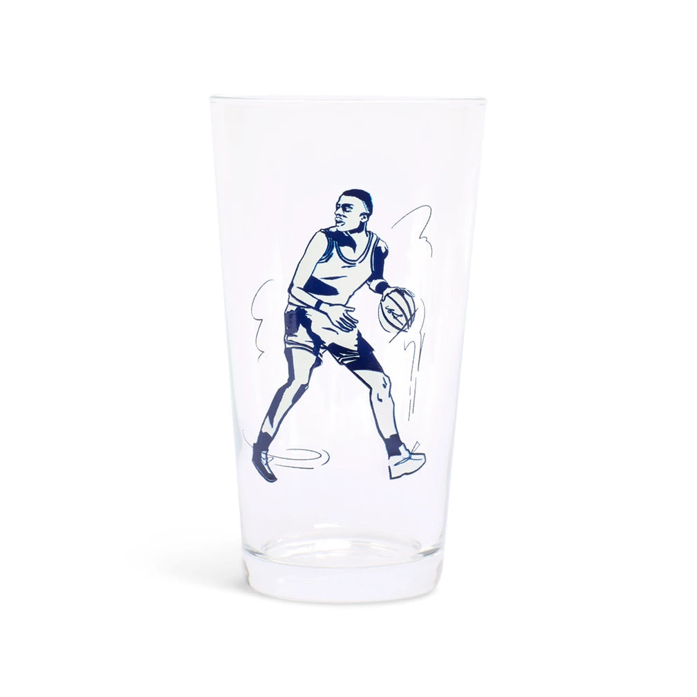 Clear pint glass with a navy illustration of a basketball player dribbling, side view