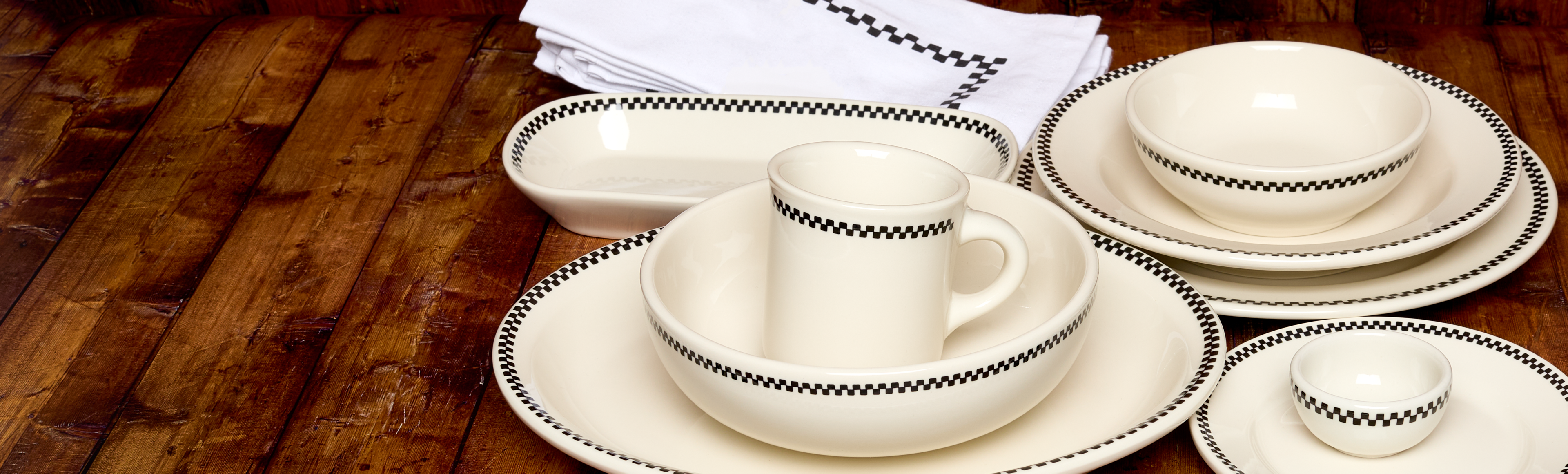 White ceramic dinnerware set with black patterns on a wooden table.
