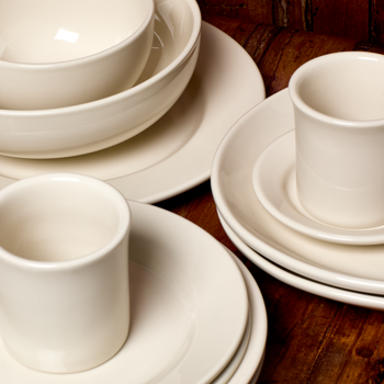 Set of white ceramic dinnerware on a wooden surface