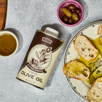 Can of olive oil with bread and olives on a table