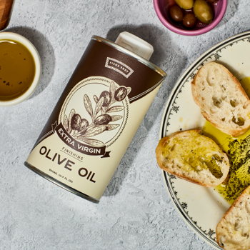 Can of olive oil with bread and olives on a table