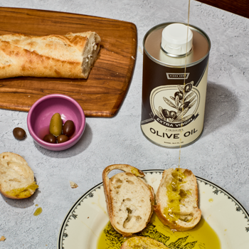 Olive oil can with bread and olives on a table
