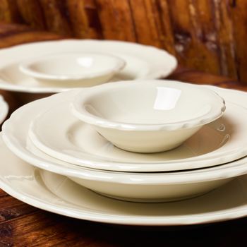 Set of white ceramic bowls and plates on a wooden surface