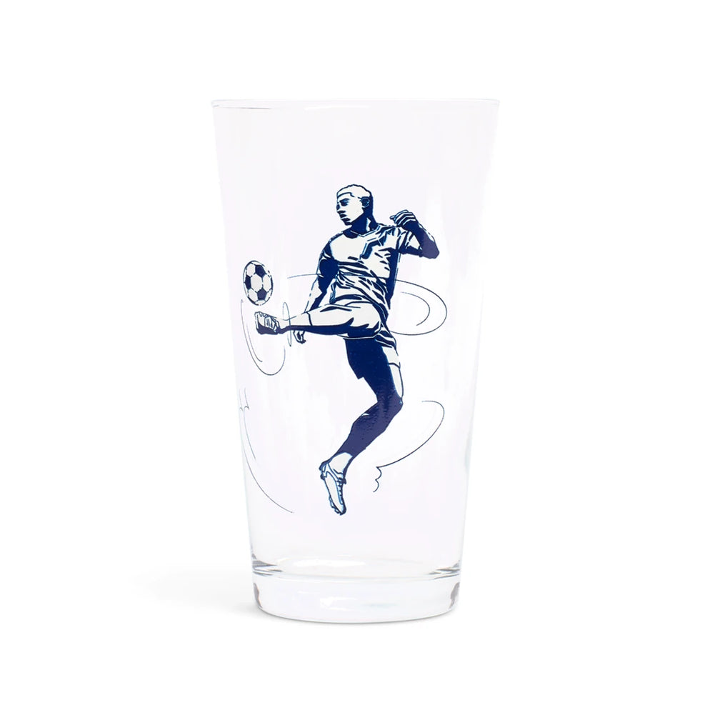 Clear pint glass with a navy illustration of a soccer player kicking a ball, side view