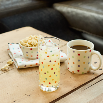 Polka dot glass with lemonade and mug with coffee on a wooden table.
