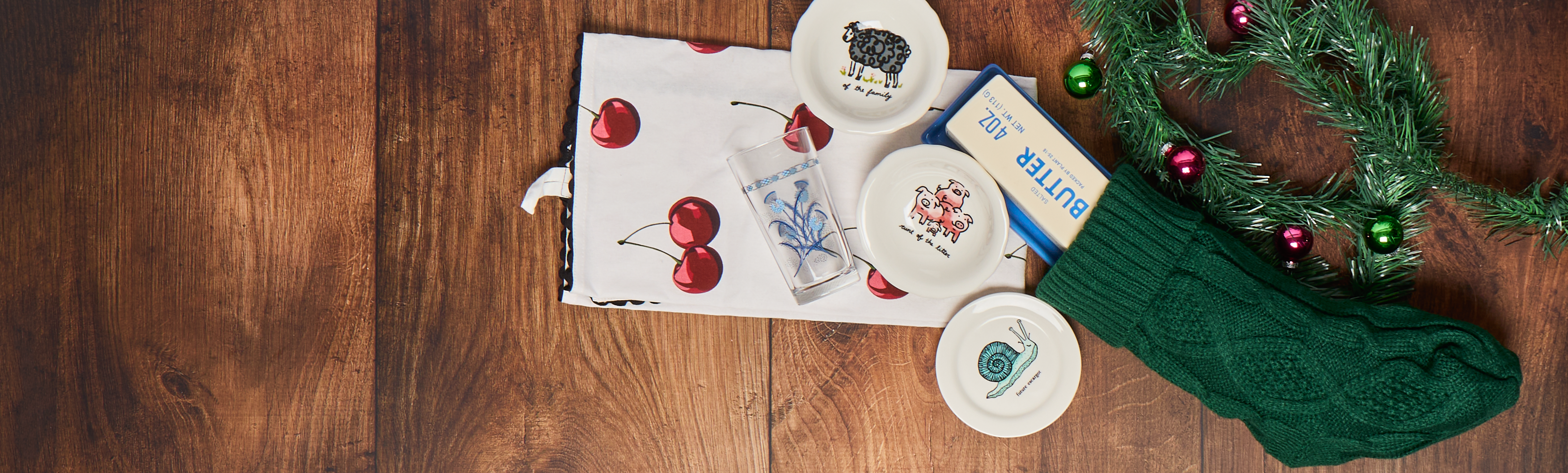 Collection of items including a box with cherry illustrations, a green knitted item, and decorative elements on a wooden surface.
