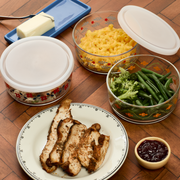 Assorted food items including meat, vegetables, and condiments on a wooden table.