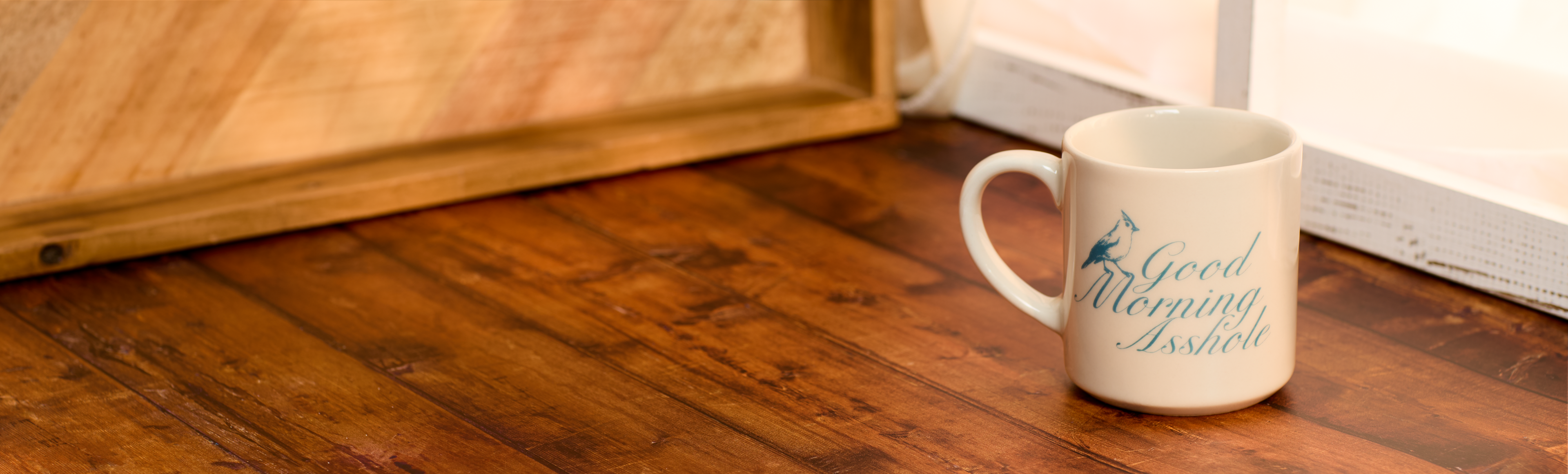 White mug with blue text on a wooden floor