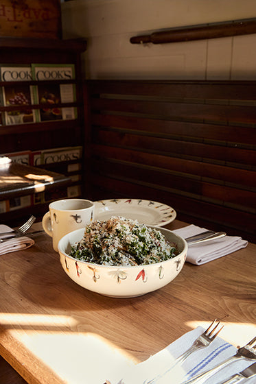 Bowl of salad on a wooden table with cookbooks in the background