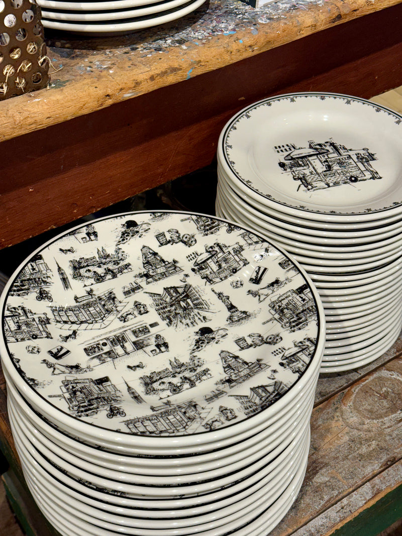 Stacks of decorative plates with black patterns on a wooden surface