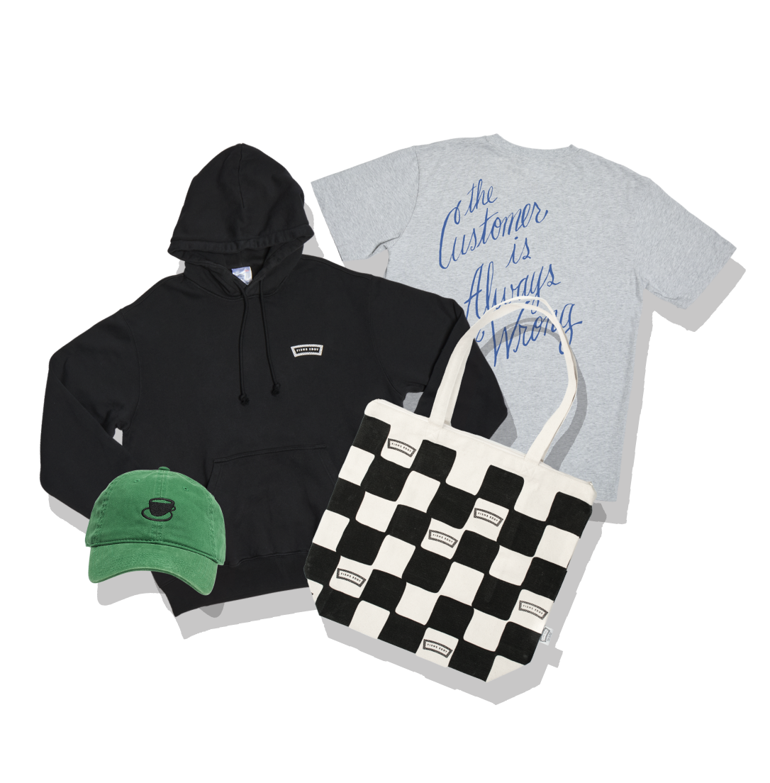 Black hoodie, green cap, gray t-shirt with text, and black and white checkered bag on a white background