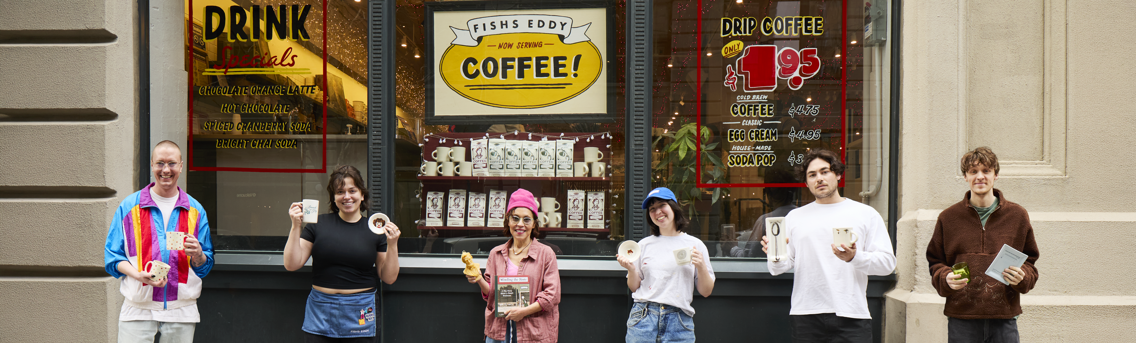 People standing in front of a coffee shop with vintage signs.