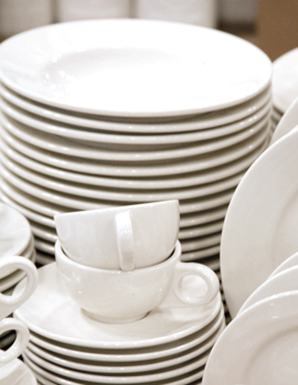 Stacks of white ceramic plates and bowls on a neutral background