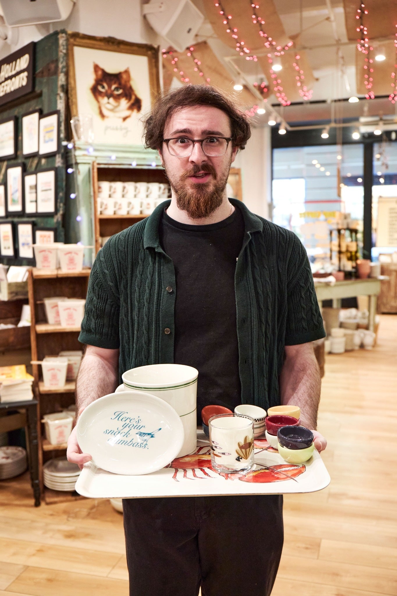 Man holding a tray with ceramic items in a store setting