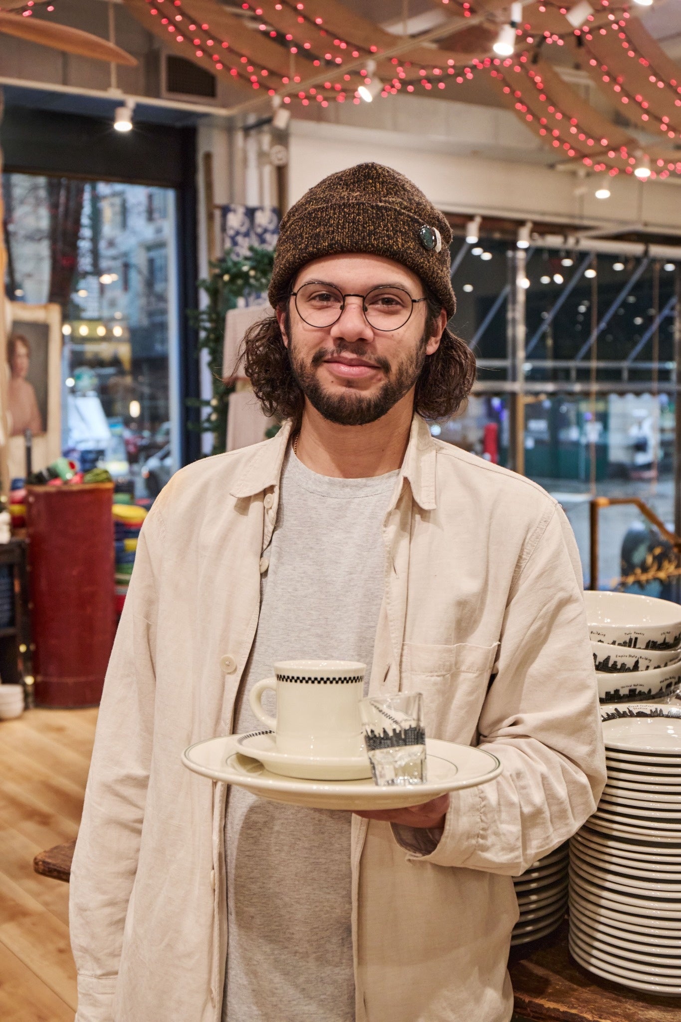 Man holding a plate with a cup and saucer in a store setting